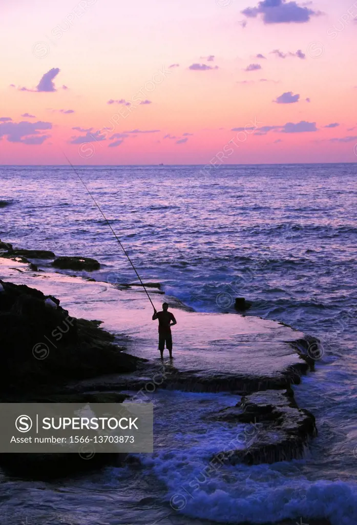 A lone fisherman casts his rod along Beirut's rocky Mediterranean