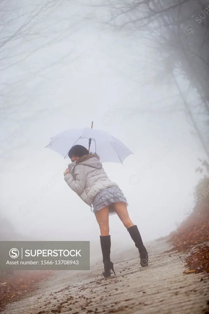 Stock Photo - Young woman under umbrella lost in fog