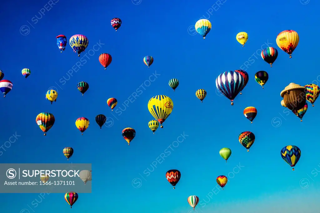Scores of hot air balloons brighten the blue morning sky in a colorful display of lighter than air flight.