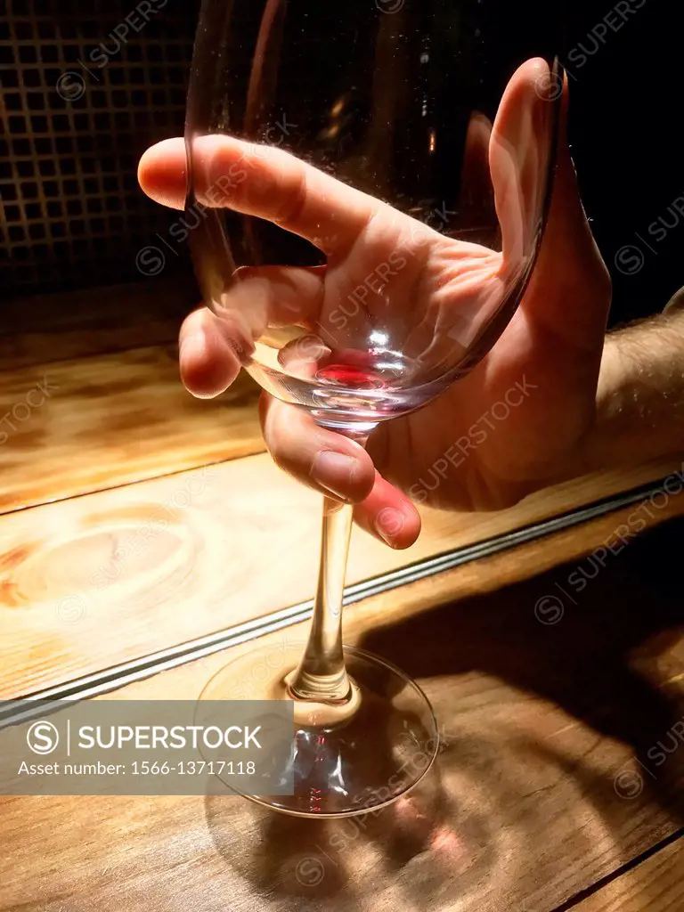 Man's hand holding an empty glass of red wine. Close view.