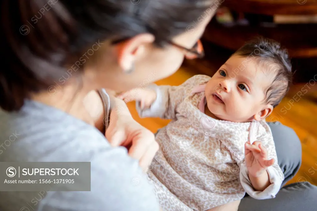 Mother interacting with baby girl at home.