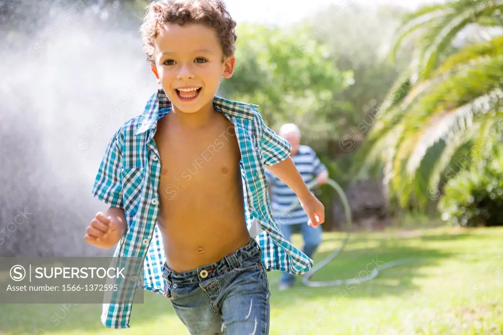 Young boy playing with his grandfather in the garden.