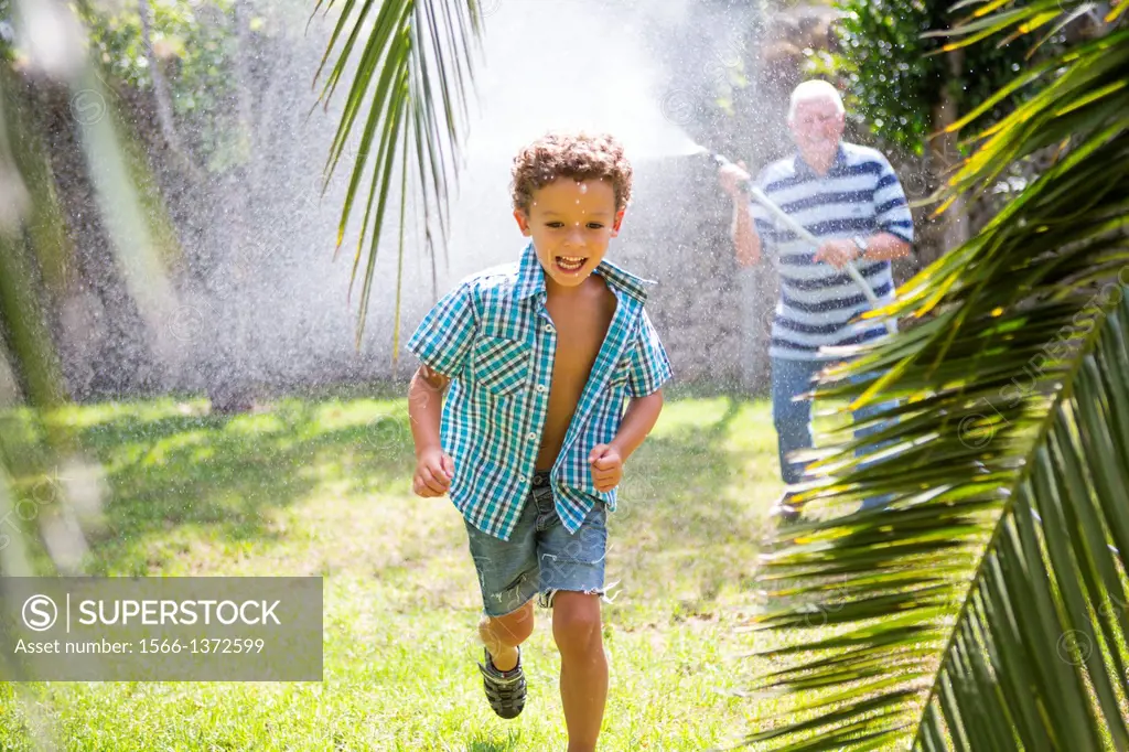 Young boy playing with his grandfather in the garden.