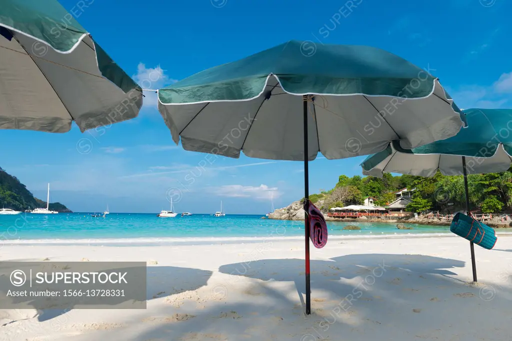 Beach umbrellas waiting for tourists in Raya island, Thailand.