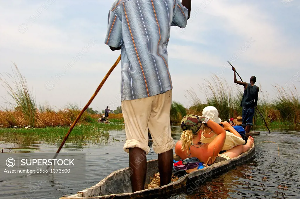 Tourists on trip in a Mokoro canoe in the Okavango Delta, Botswana.