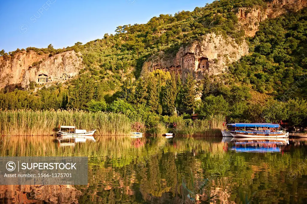 Boats on Dalyan Çay River with Lycian Rock Tombs in the cliffs . Mediterranean coast Turkey.