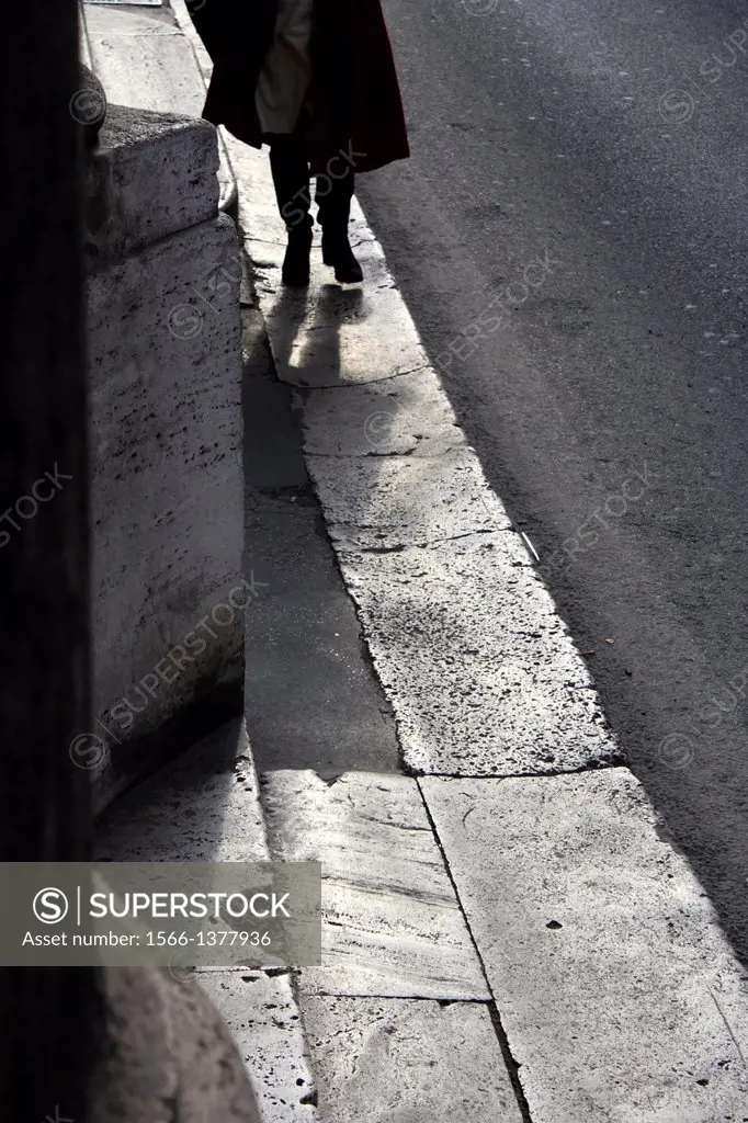 woman walking on pavement in street road in rome italy.