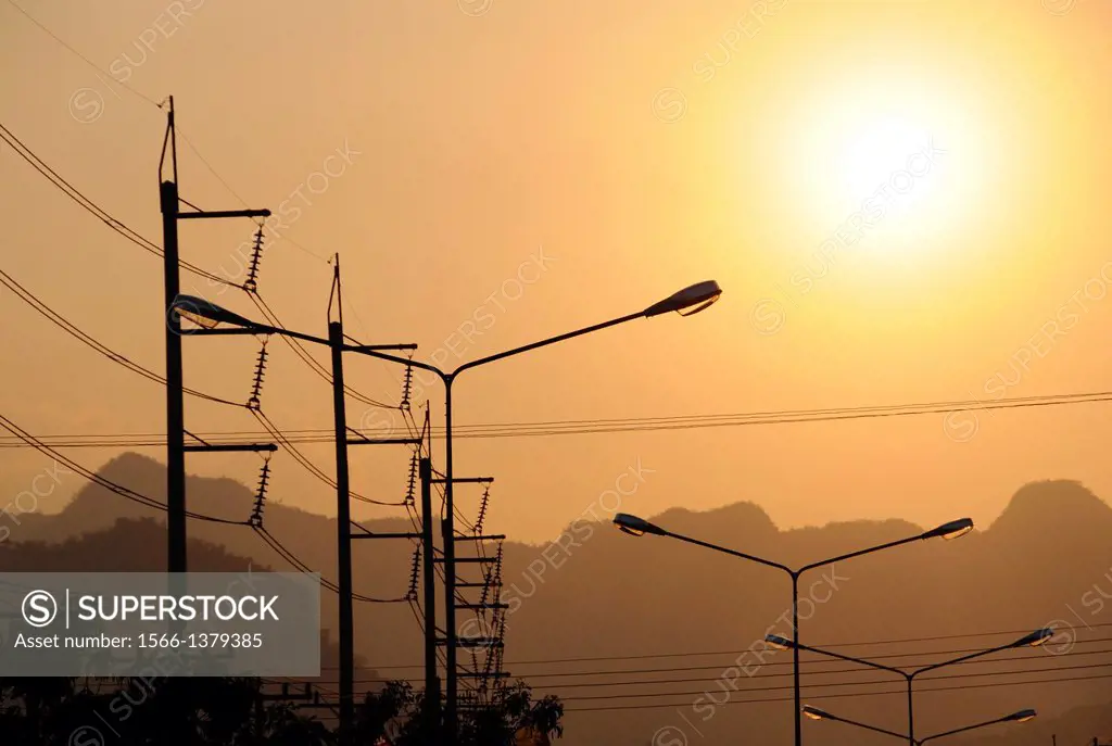 Silhouettes of power lines and street lamps in the backlight