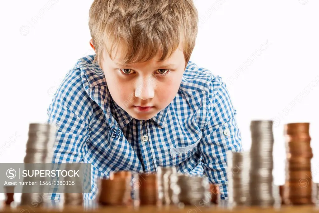 A young boy of 10 counts his money and stacks it up.