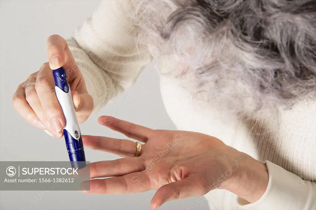 Close up of Senior woman´ hands using a lancet for blood sugar testing for diabetes