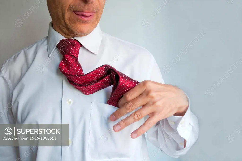 Man putting his tie into the pocket of his shirt. Close view.
