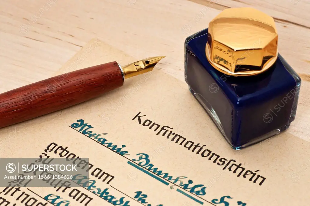 Detail photo of a German confirmation attestation from the year 1951, on it a inkpot and a pen.