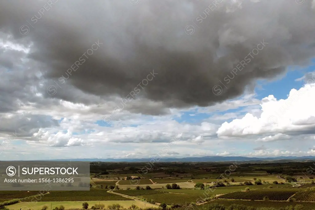 A storm cloud hangs over the farmlands of the Herault