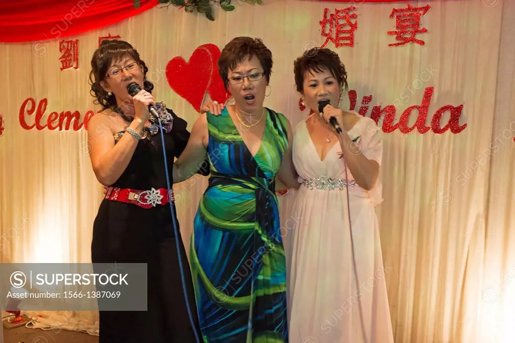 Three sisters having karaoke session at wedding party, Kuching, Sarawak, Malaysia.