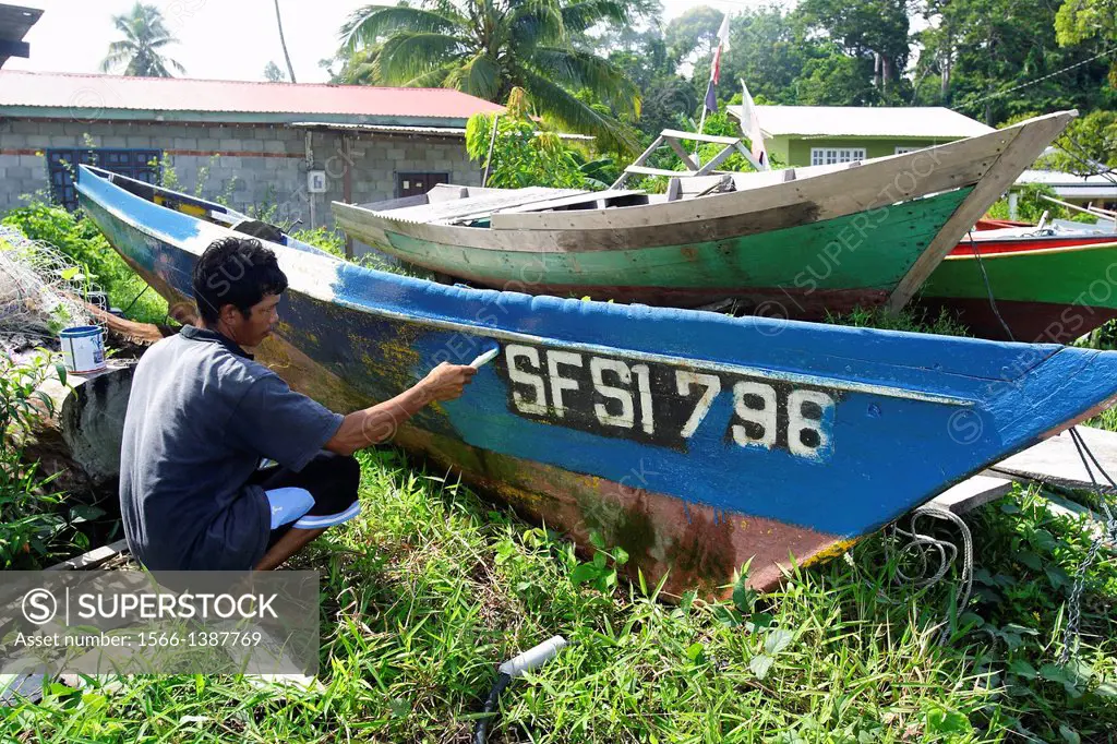 man painting fishing boat, Mabul Island, Sabah, Malaysia, Borneo