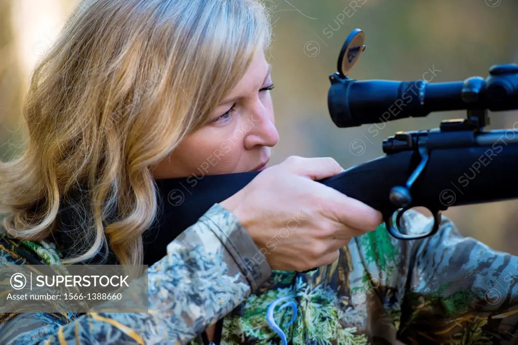 A woman hunter aims her Winchester.
