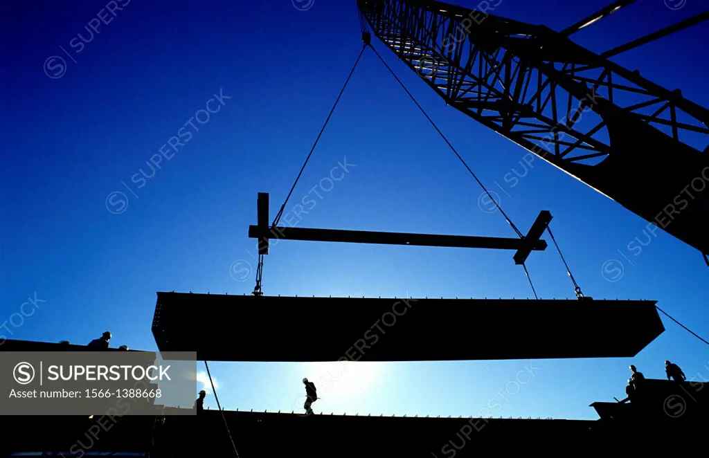 Construction Crane lifting heavy I beam into place.