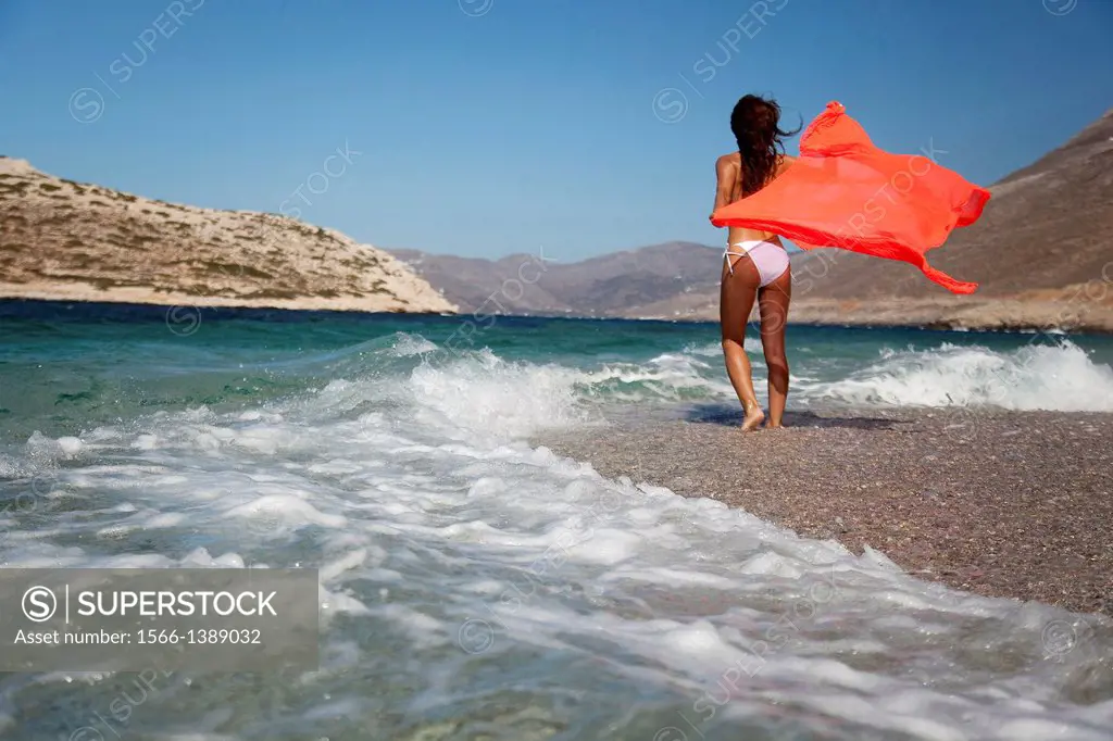 Woman in bikini walking towards the waves at the beach, Amorgos, Cyclades Islands, Greek Islands, Greece, Europe.