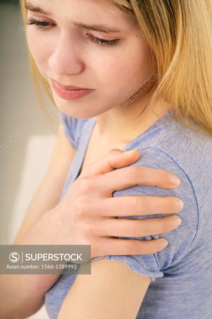 Young beautiful woman holding her stiff painful shoulder