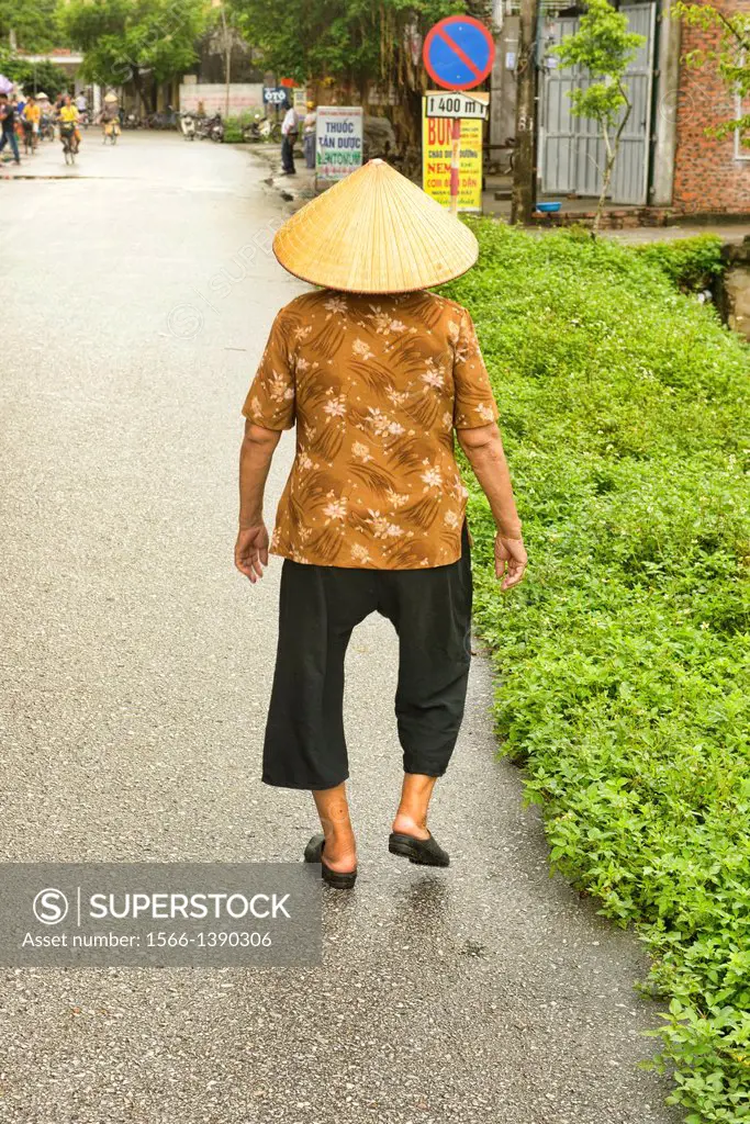 old Vietnamese woman walking, Ninh Binh, Vietnam.