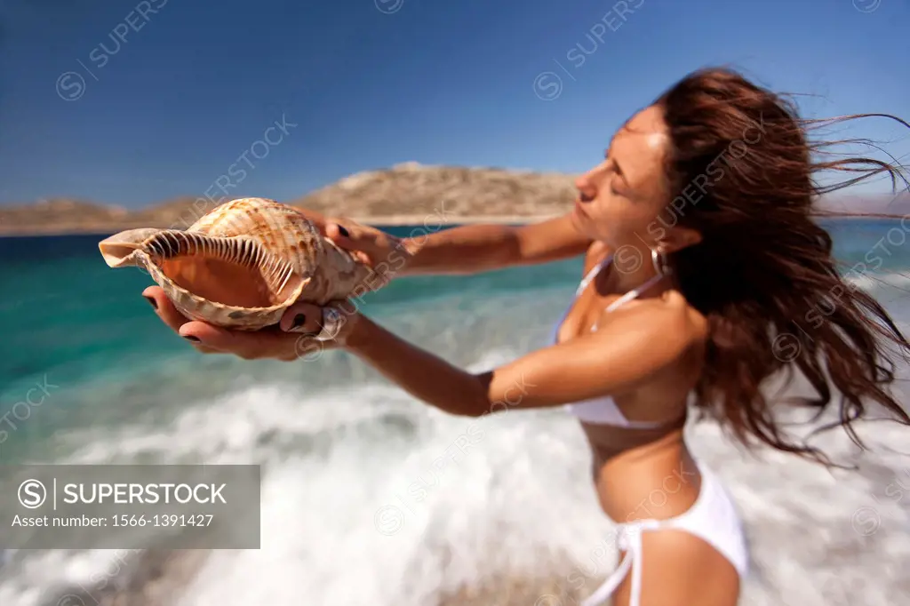 Woman holding a shell in her hand, Naxos, Cyclades Islands, Greek Islands, Greece, Europe.