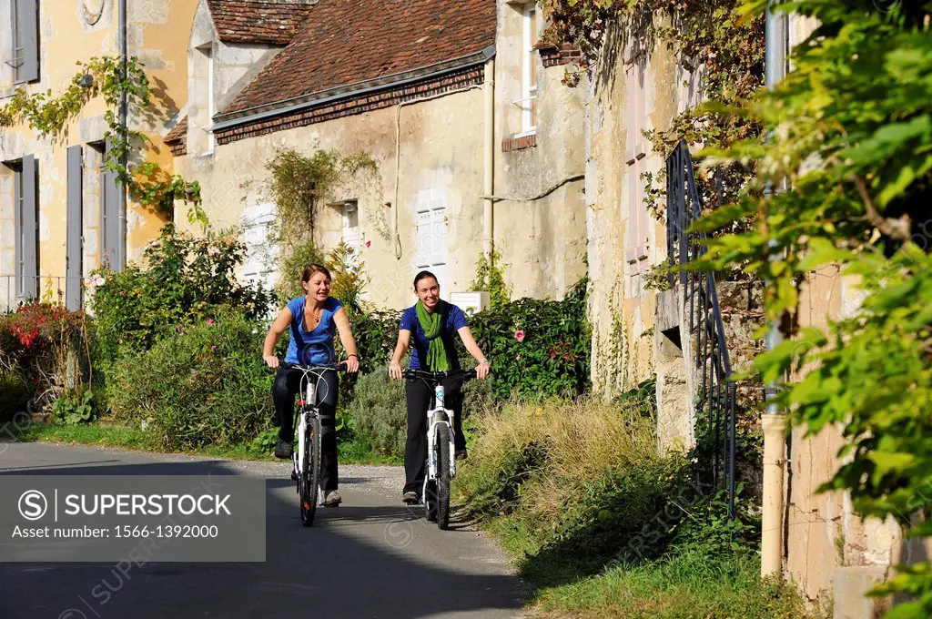 young women cycling in the village of Villeray, Commune of Condeau, Orne department, Lower Normandy region, France, Western Europe.