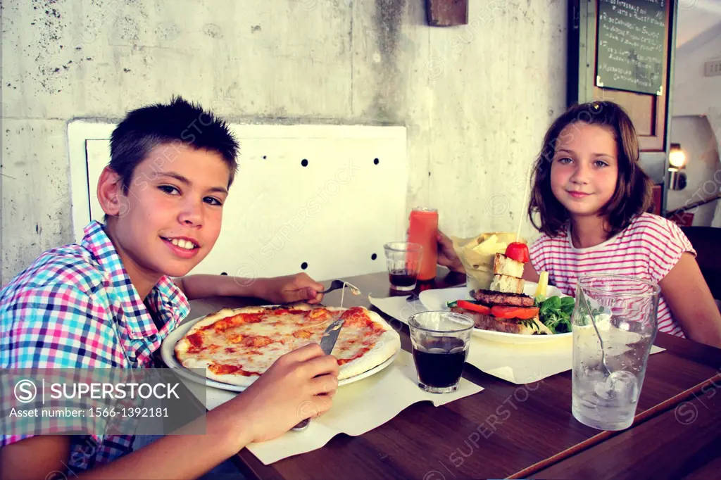 Two children eating in a slow food restaurant, Rome, Italy