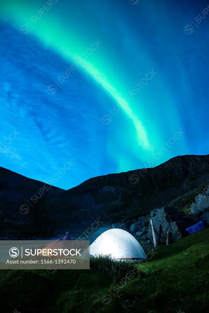Illuminated tent with Northern Lights in sky at Kvalvika beach, Moskenesoy, Lofoten Islands, Norway.