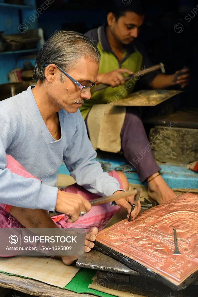 India, Uttar Pradesh, Varanasi, Craftsmen embossing copper plates.