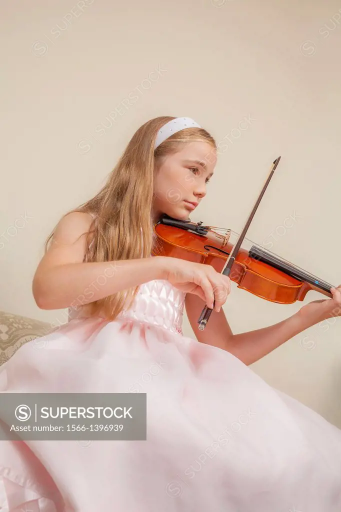 Preteen blond girl practicing the viola.