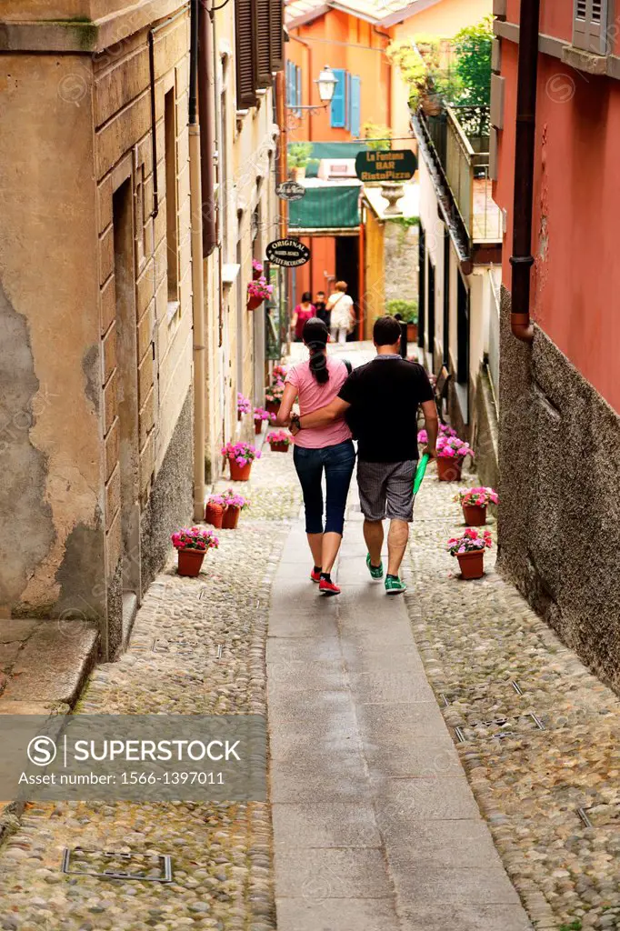 Couple walking down a cobbled street in Bellagio on the shores of Lake Como in northern Italy.