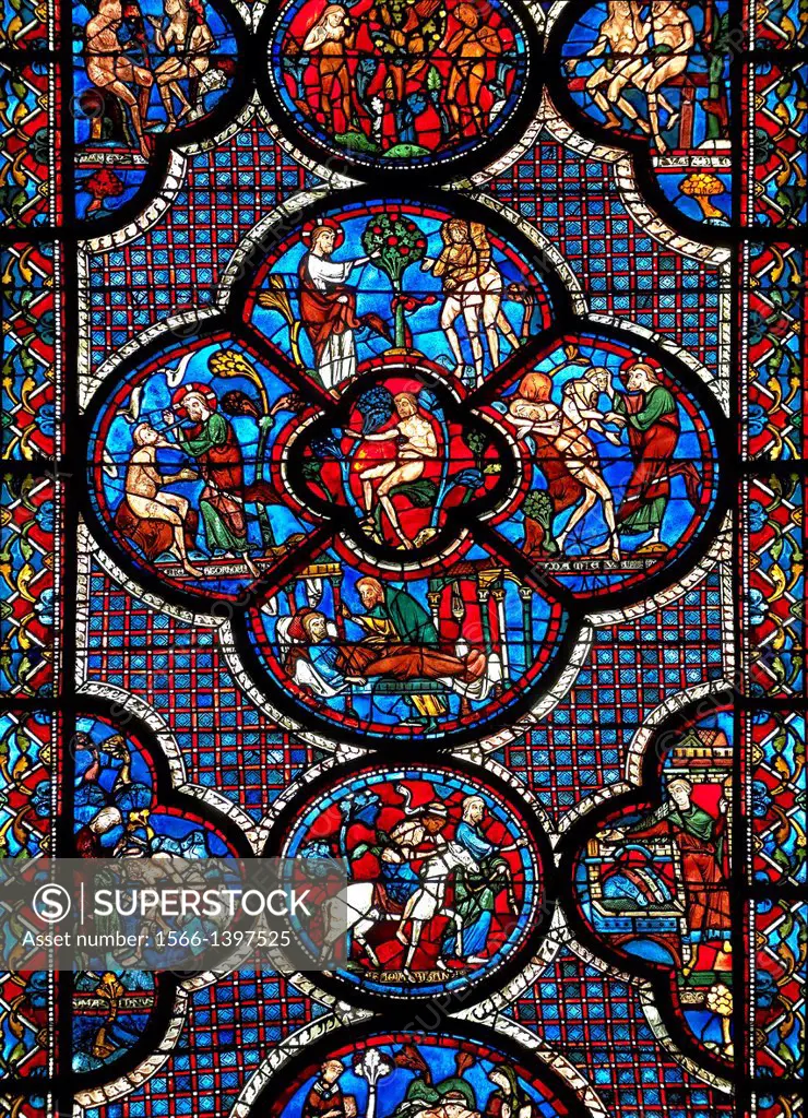 Medieval stained glass Window of the Gothic Cathedral of Chartres, France - dedicated to the lGood Samaritan . Central panel shows Adam dwelling in Pa...