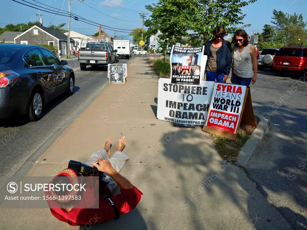 Political protest on sidewalk in Vineyard Haven, Martha's Vineyard, Massachusetts. A proessional photographer is documenting the event for a local pap...