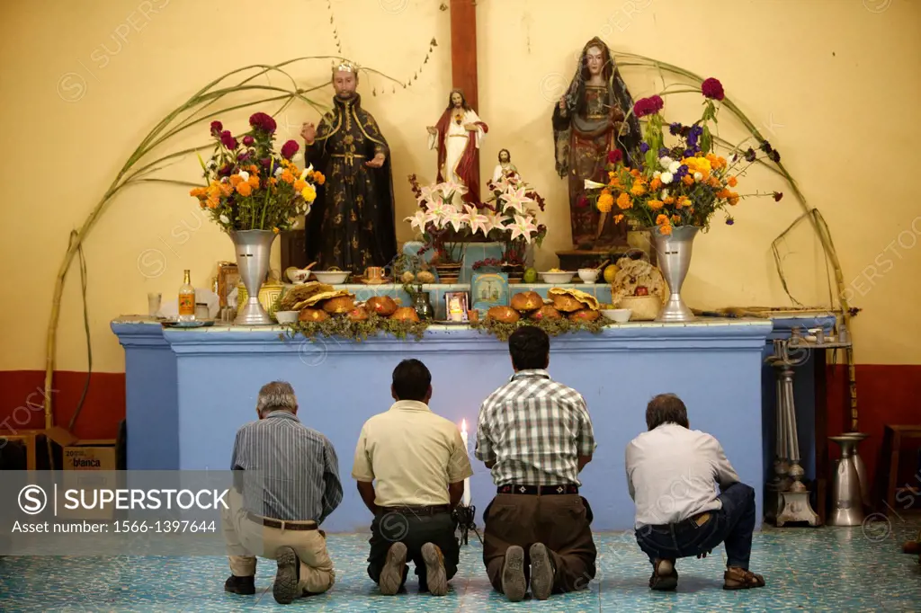 Men pray as they kneel in front of an altar during the Day of the Dead celebrations in Teotilan del Valle, Oaxaca, Mexico. The Day of the Dead celebra...