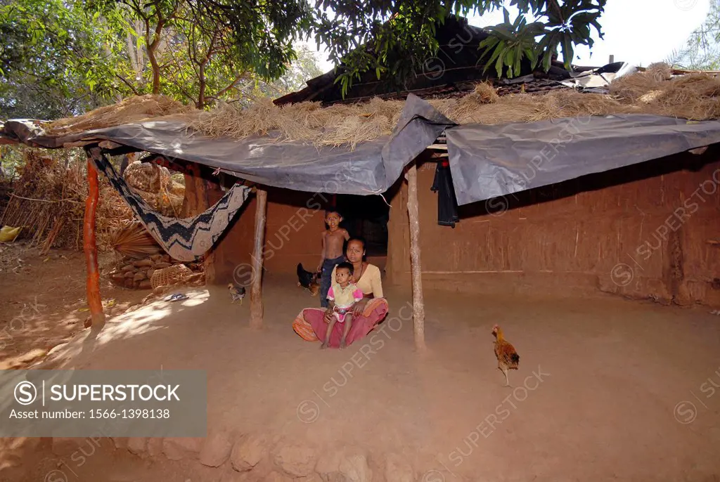 Woman with her children sitting outside hut, Bhil Tribe, Madhya Pradesh, India.