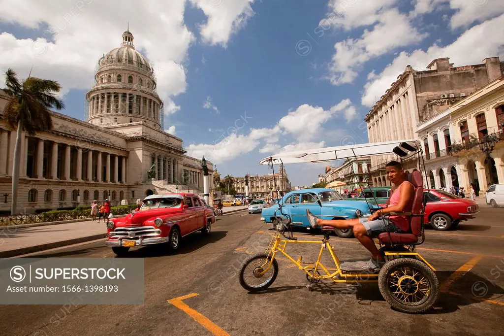 Street scene of old American cars used as taxis and bici-taxi in front of the Capitolio building in Central Havana, Cuba, West Indies, Central America...