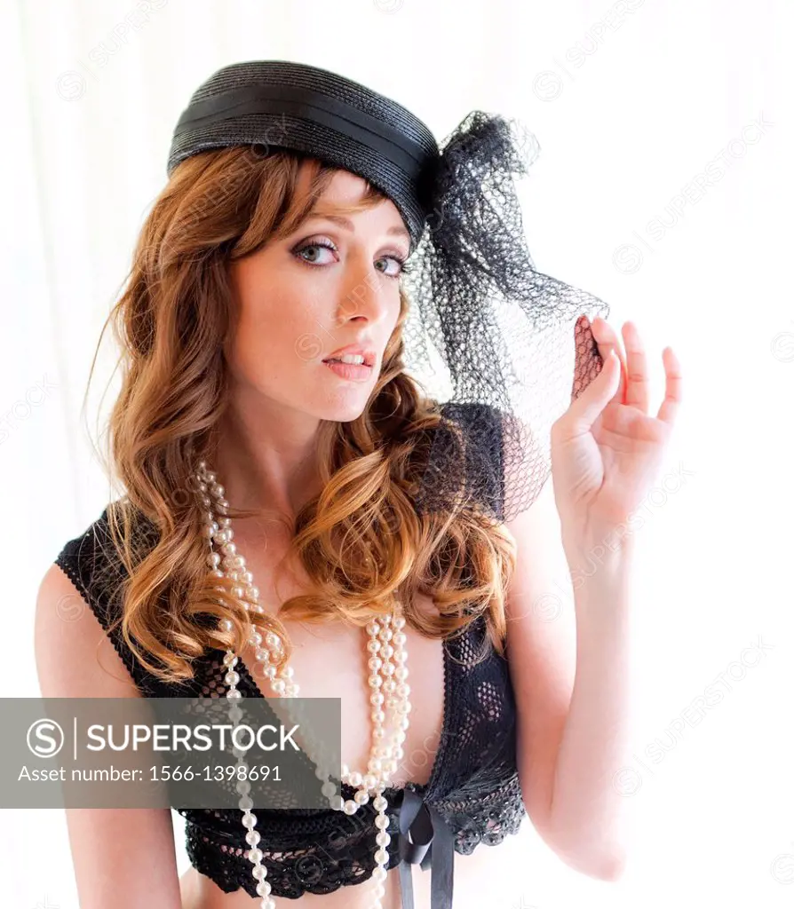 Portrait of a 31 year old redhead woman wearing a hat with a black veil.