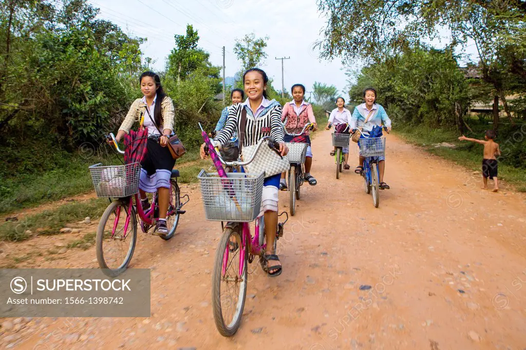 Children returning home after school on thier bicycles, Vang Vieng, Laos.