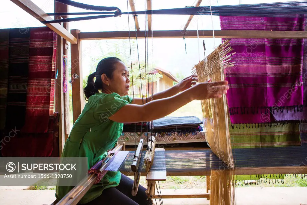 Lao woman making traditional fabric on her loom near Vang Vieng, Laos.