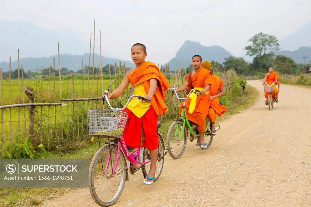 Young novice monks commuting to their temple on bicycles near Vang Vieng, Laos.