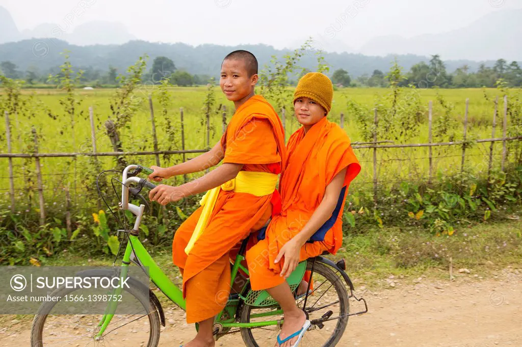 Young novice monks commuting to their temple on bicycles near Vang Vieng, Laos.