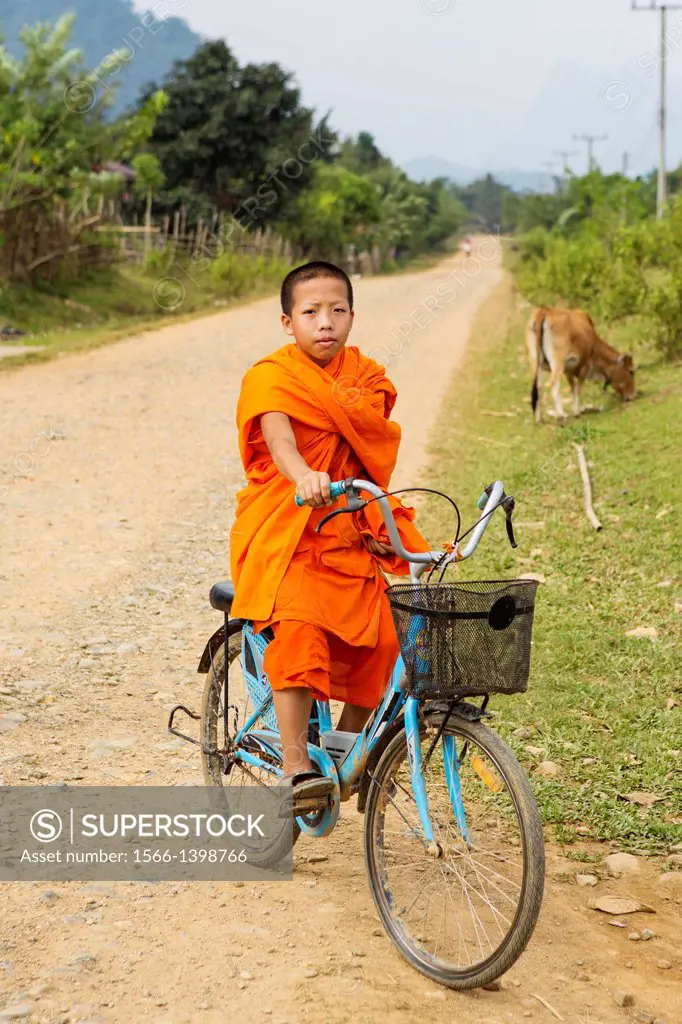 Young novice monk commuting to their temple on bicycles near Vang Vieng, Laos.