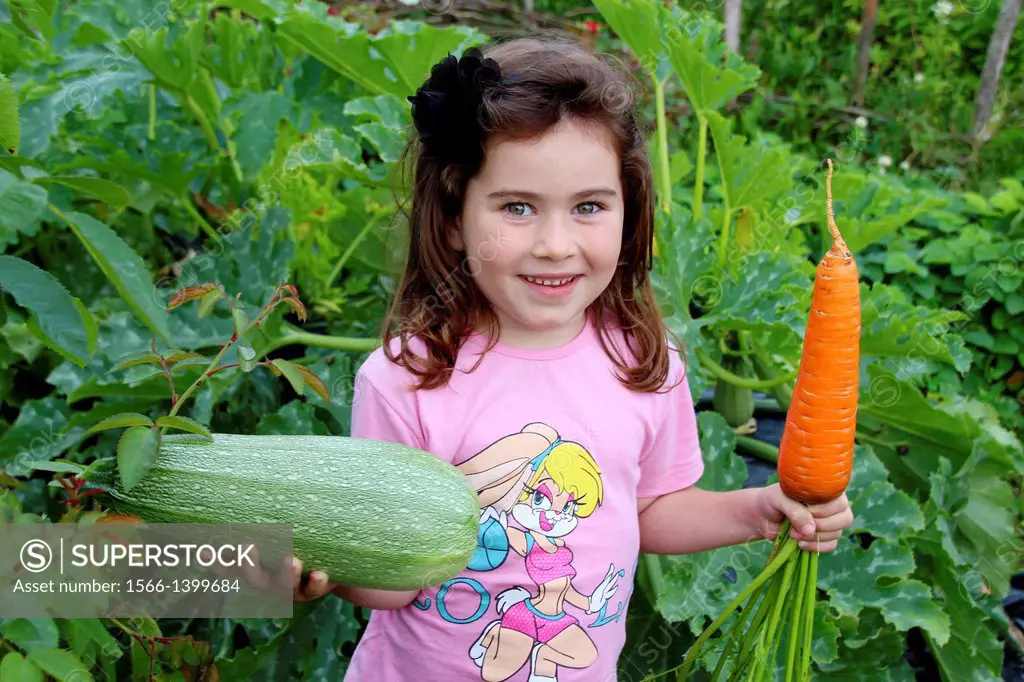 Small girl with big carrot and courgette, Primorsk, Russia.