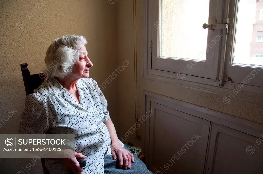 Portrait of elderly woman at home, sitting by the window.