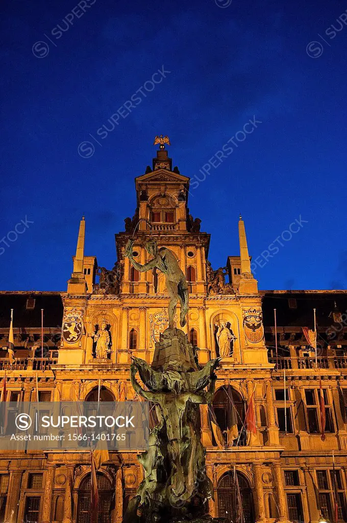 Europe, Belgium, Antwerp. Brabo Fountain at night, the Stadhuis (town hall) in the background.
