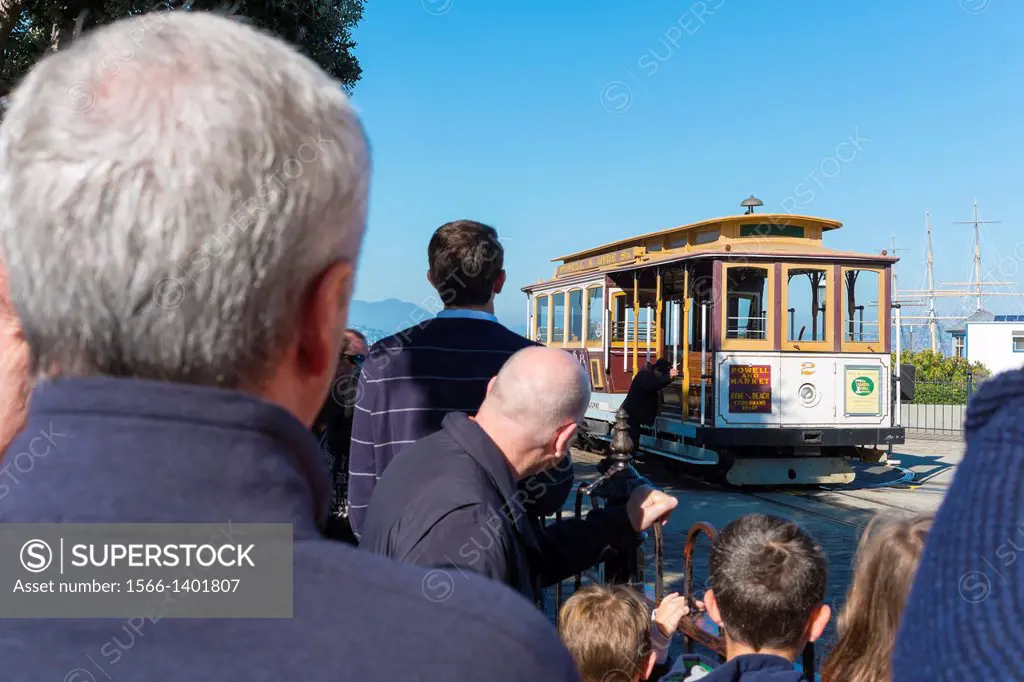San Francisco Cable Car. Passengers are watching a cable car being turned on a turn table at Fisherman´s Wharf while waiting for boarding.