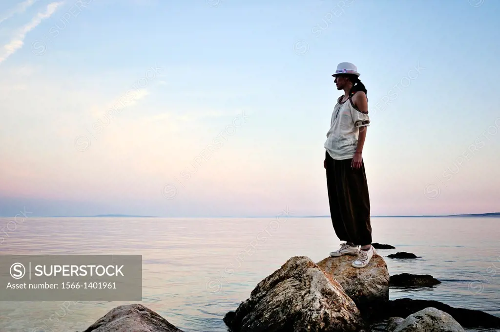 Woman standing on rock watching sunset, Island Pag, Croatia, Europe.