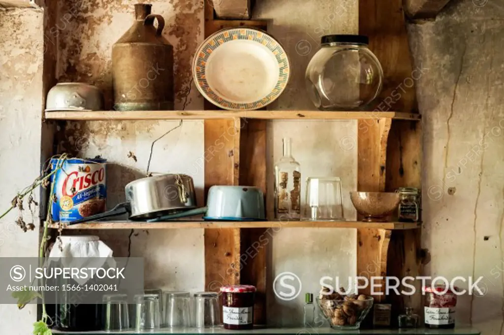 Old pots and dishes on wooden shelves in the kitchen of an old French farmhouse, Anzême, Creuse Department, France.