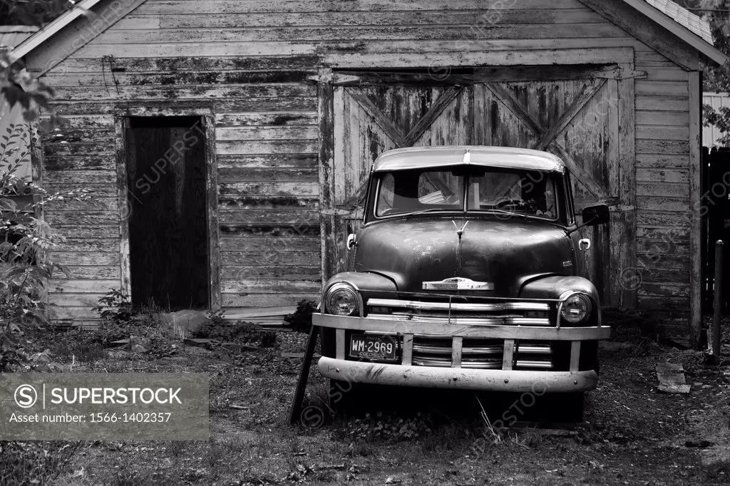 Abandoned and disused Chevrolet pickup truck parked outside a wooden shed, Colorado, USA.