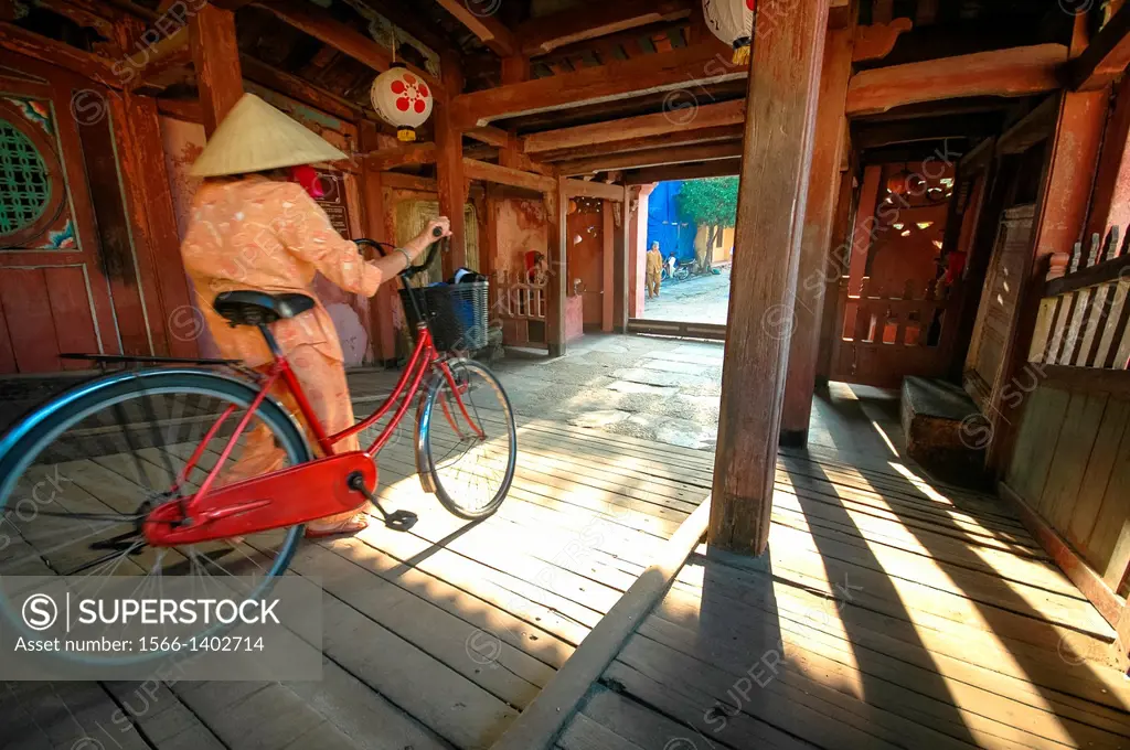 cyclist crossing the famous wooden bridge of Hoi An, Vietnam